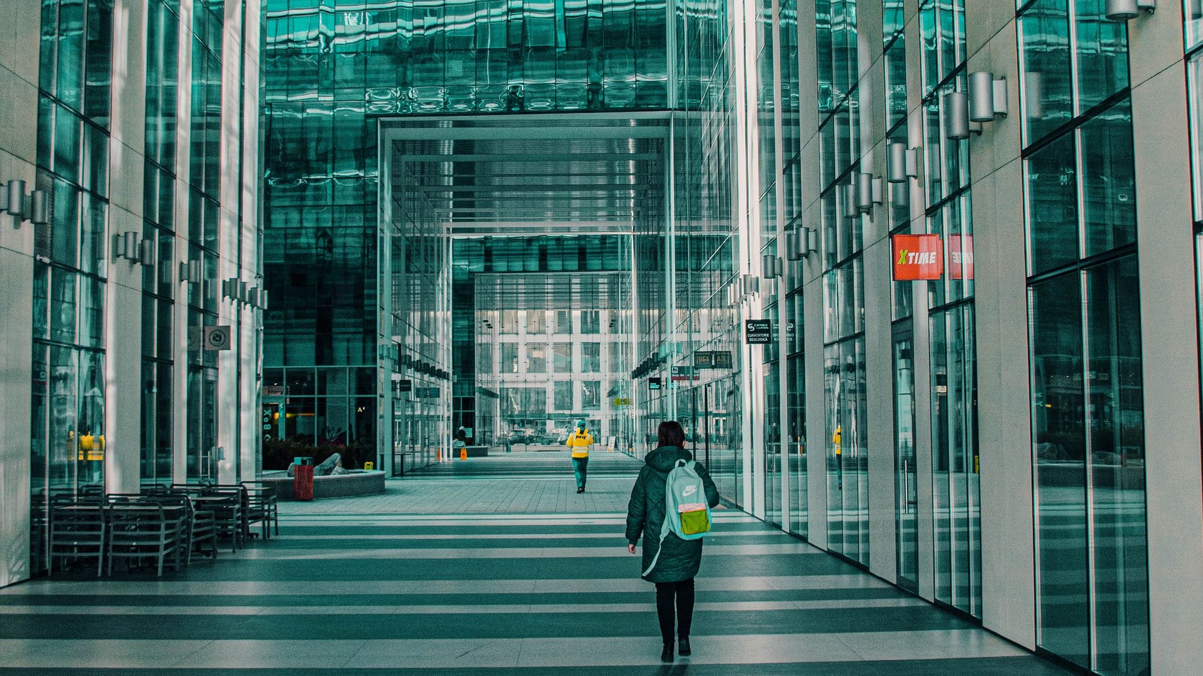 Person walking through a modern glass corridor, representing process complexity flowing into clarity and efficiency.